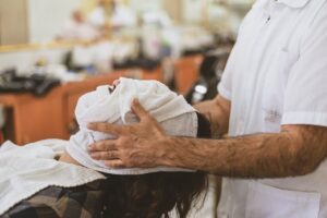 Man receiving a soothing face massage with a towel at a contemporary barber shop.